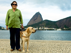 foto da Ethel e o co guia Cesar no Aterro do Flamengo com o Po de Acar ao fundo.