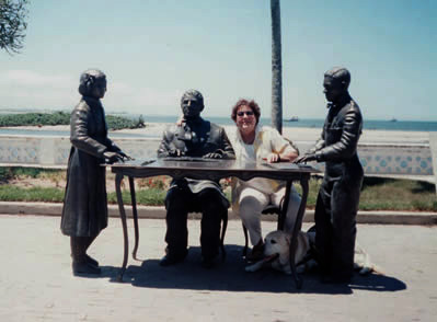 foto da escultura em bronze de Louis Braille ensinando braile, a um menino e uma menina do sculo 19, Ethel sentadada ao seu lado e o co guia Gem deitado sob a mesa - Maca - Estado do Rio de Janeiro